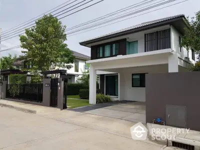 Modern two-story house with driveway and lush greenery in suburban neighborhood.