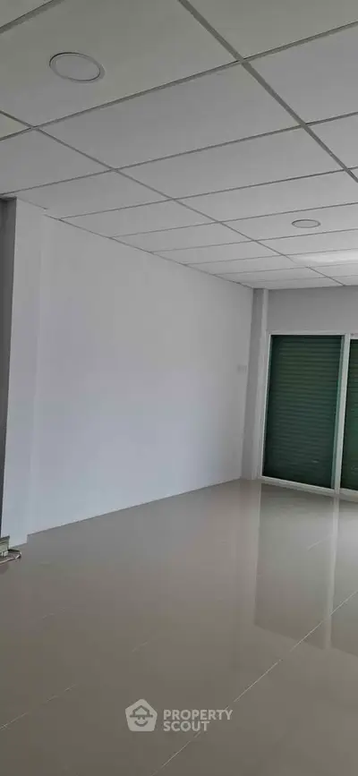 Spacious empty room with glossy tiled floor and modern ceiling design, perfect for customization.