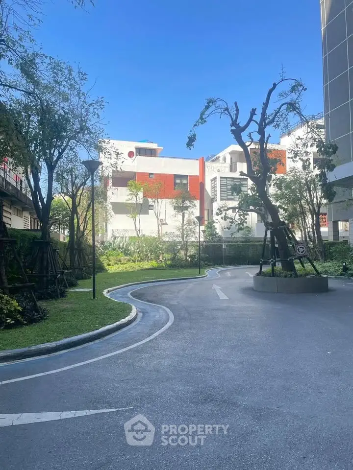 Modern residential building with lush garden and driveway in urban setting.