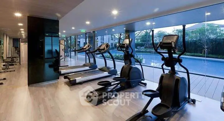 Modern gym with pool view in luxury residential building.