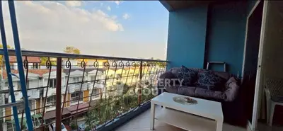 Charming balcony with cozy seating and scenic view of rooftops and sky.