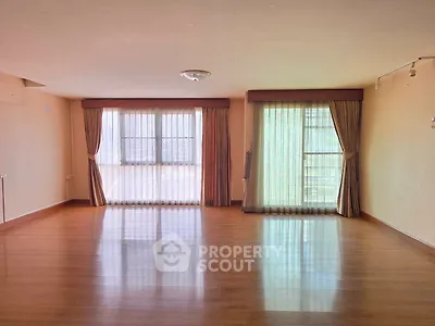 Spacious empty living room with large windows and wooden flooring