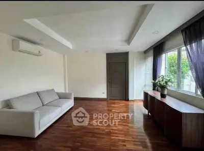 Spacious living room with wooden flooring and modern furniture, perfect for relaxation.
