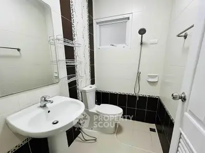 Modern bathroom with sleek fixtures and neutral tiles, featuring a shower and toilet.