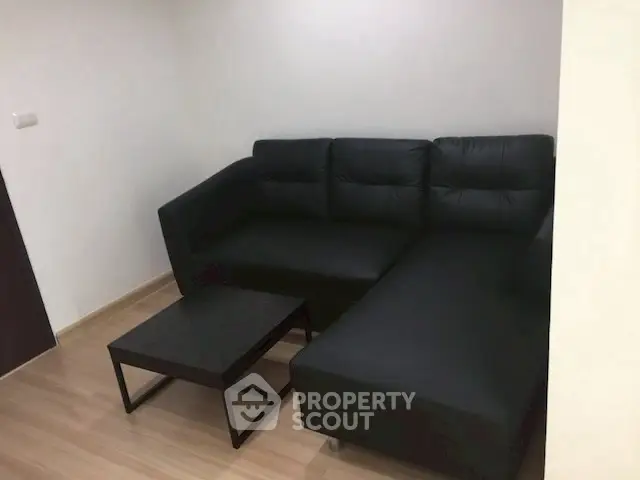 Modern living room with sleek black sectional sofa and minimalist coffee table.