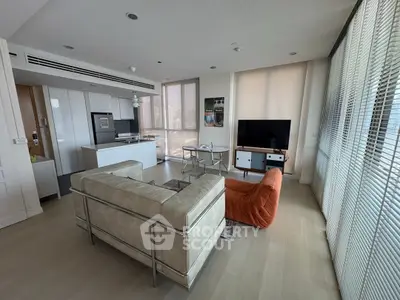 Modern living room with sleek furniture and large windows offering city views.