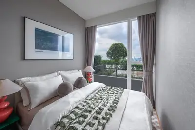 Cozy bedroom with large window offering a stunning garden view, elegant decor, and plush bedding.