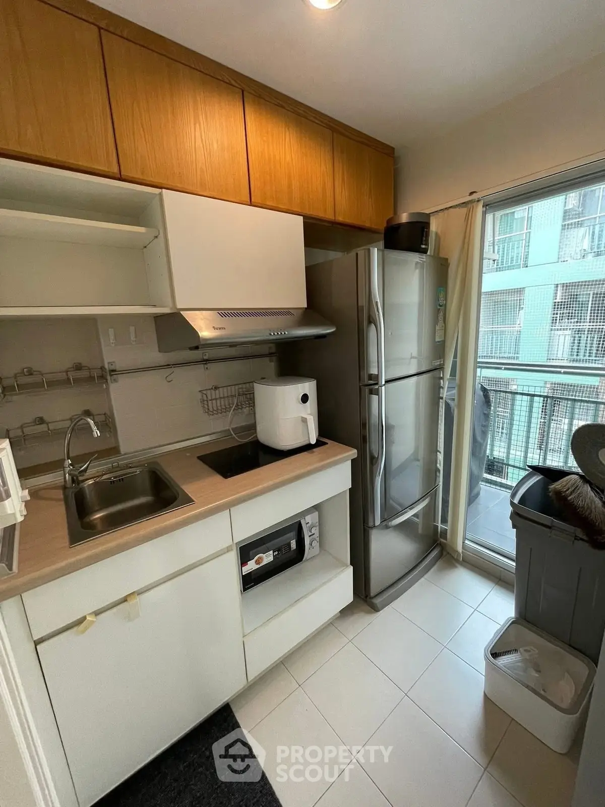 Compact kitchen with modern appliances and balcony view in urban apartment