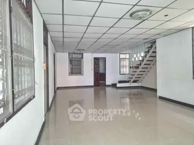 Spacious interior with tiled floors and staircase, ideal for customization.