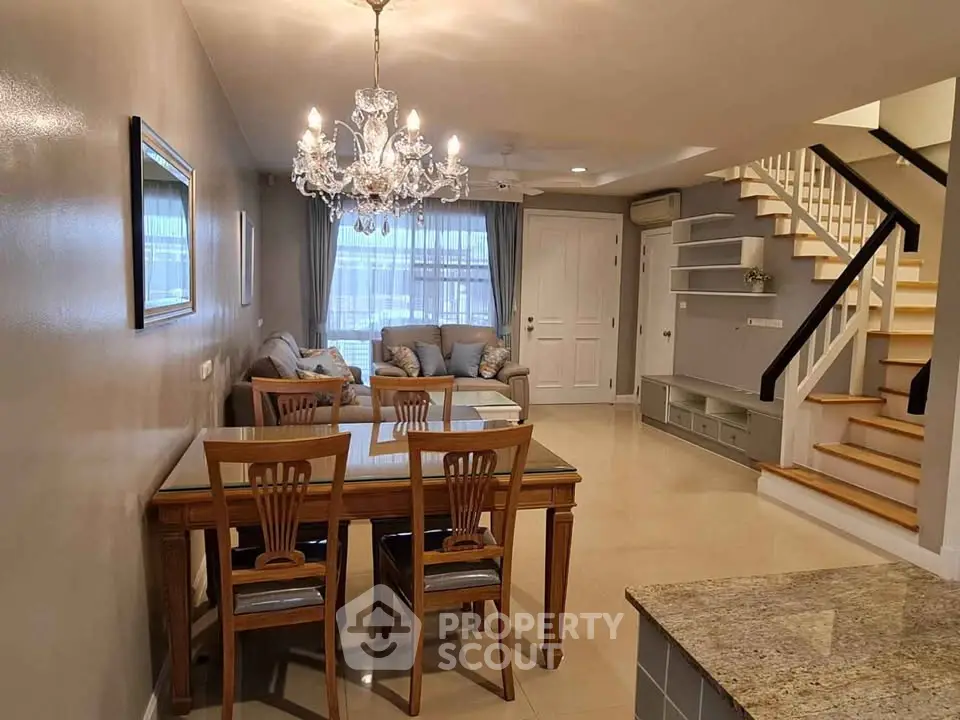 Elegant living room with chandelier, dining area, and staircase in modern home