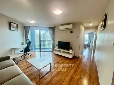 Spacious living room with modern decor and city view balcony in high-rise apartment.