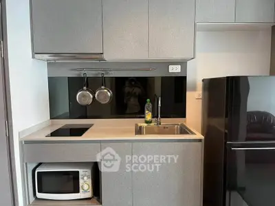 Modern compact kitchen with sleek cabinetry, induction cooktop, and built-in microwave in urban apartment.