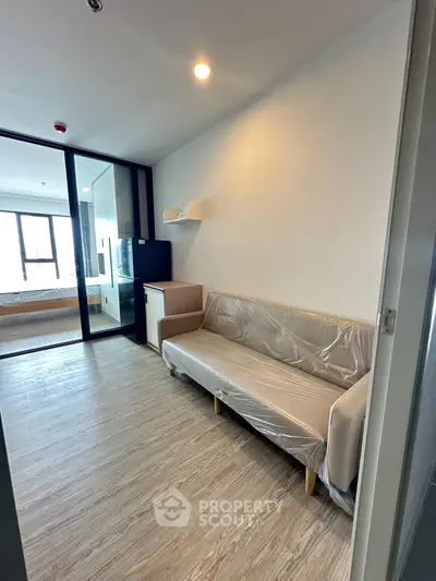 Modern apartment interior with sleek flooring and stylish furniture, featuring a cozy living area and a glimpse of the bedroom.