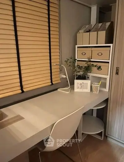 Elegant home office nook with a sleek white desk, modern chair, and tasteful storage solutions, complemented by warm wooden blinds.