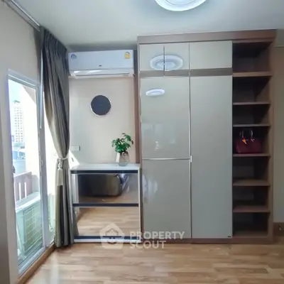 Modern bedroom with large wardrobe and city view window, featuring sleek wooden flooring and stylish decor.