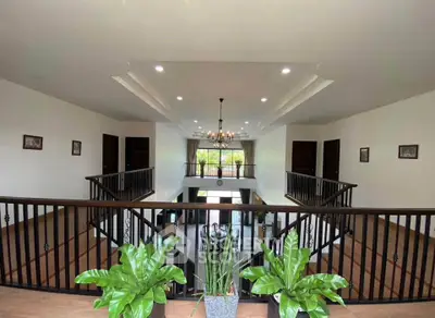 Spacious two-story living area with elegant railing and lush indoor plants