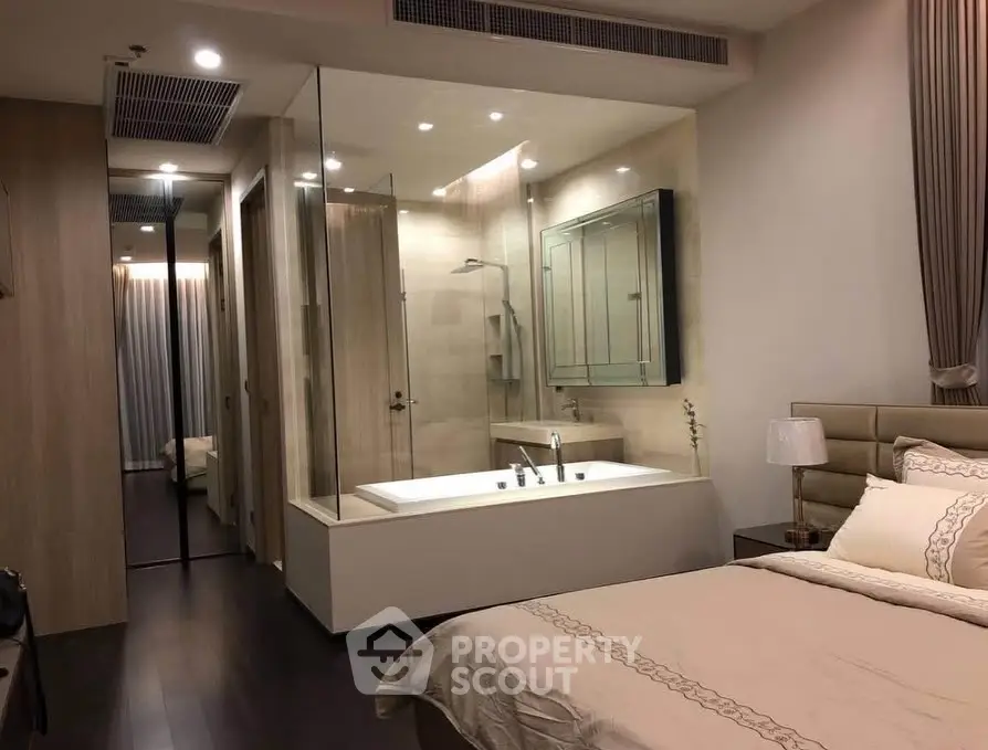 Luxurious bedroom with integrated glass-enclosed bathtub and elegant decor.
