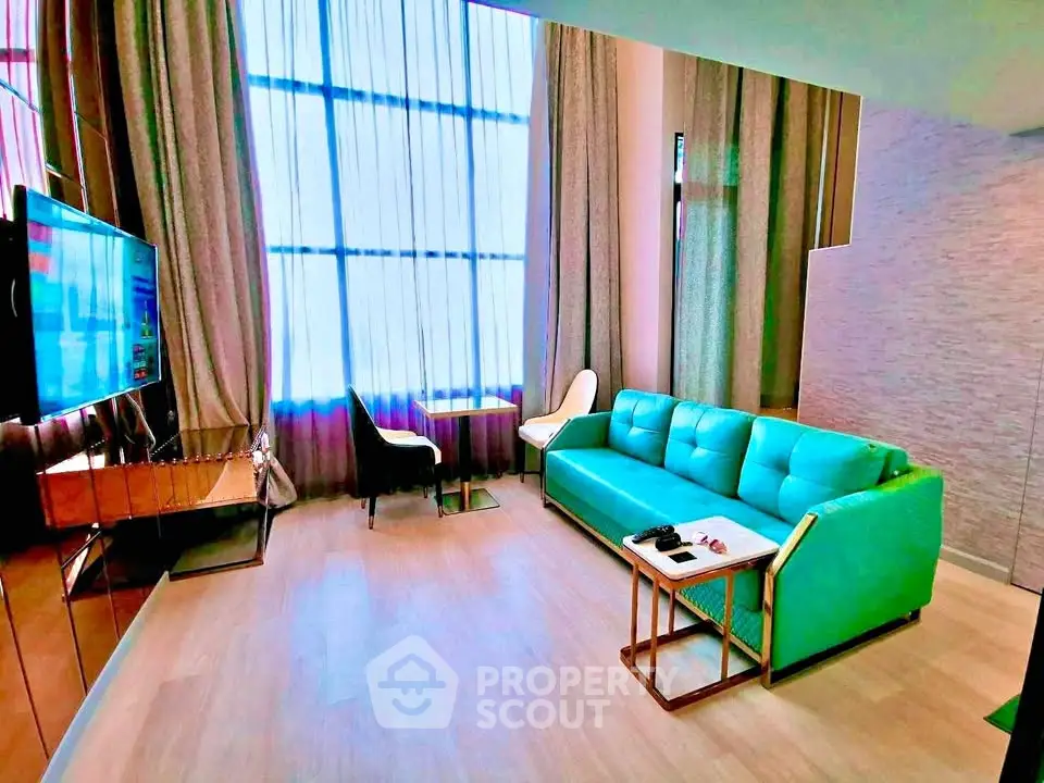 Modern living room with teal sofa and large window, featuring stylish decor and natural light.