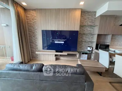 Modern living room with large TV, stylish furniture, and open kitchen layout in a contemporary apartment.
