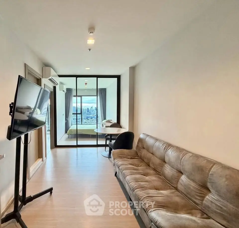 Modern living room with sleek design and city view, featuring a comfortable sofa and wall-mounted TV.