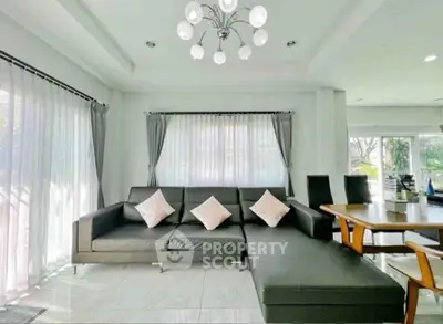 Spacious modern living room with sleek black sectional sofa and elegant chandelier, perfect for relaxation and entertaining.