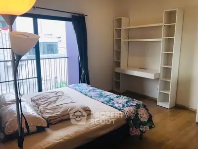 Cozy bedroom with balcony access and built-in shelving, perfect for modern living.