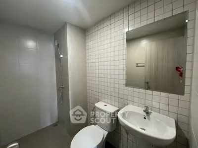 Modern bathroom with sleek fixtures and minimalist design, featuring a shower and white tiles.