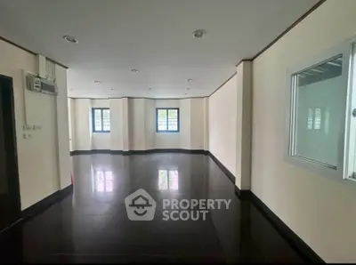 Spacious modern room with glossy black flooring and large windows for natural light.