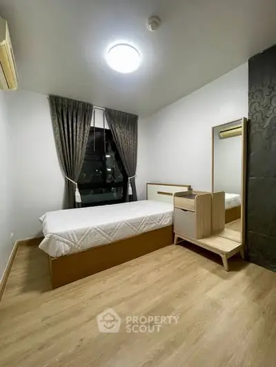 Modern bedroom with wooden flooring and elegant curtains, featuring a cozy bed and stylish furniture.