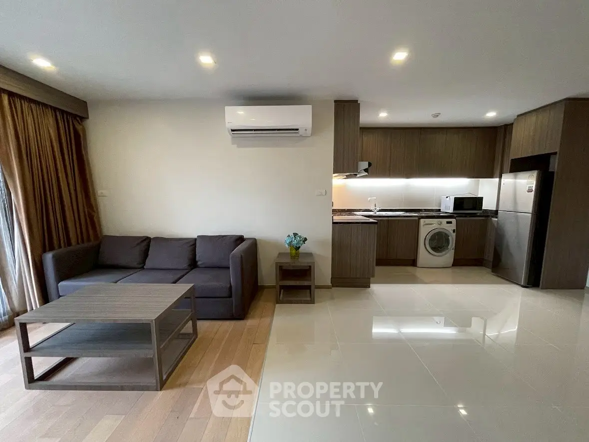 Modern open-plan living room with kitchen featuring sleek appliances and stylish furniture.