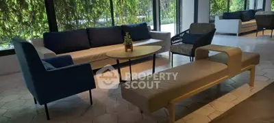 Modern living room with stylish furniture and large windows overlooking greenery.