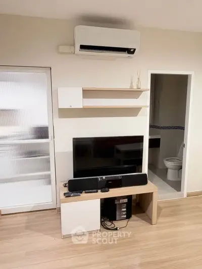 Modern living room with air conditioning and entertainment center, featuring sleek wooden flooring and minimalist decor.