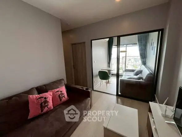 Modern living room with cozy seating and balcony view in stylish apartment.
