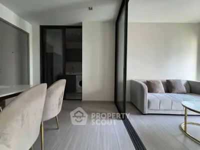 Modern living room with elegant furniture and a glimpse of a compact kitchen area.