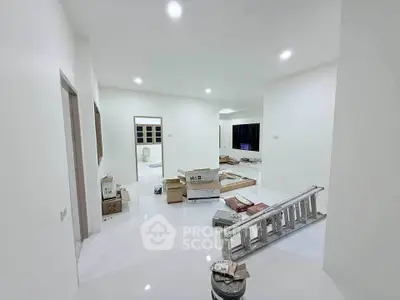 Spacious under-construction living room with white walls and scattered renovation materials.
