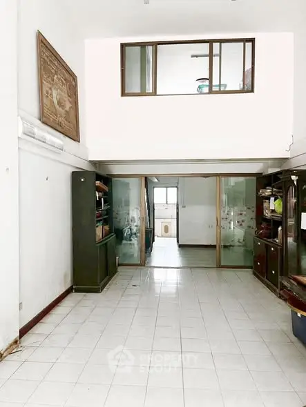 Spacious two-story interior with tiled flooring and large windows, ideal for creative renovation.