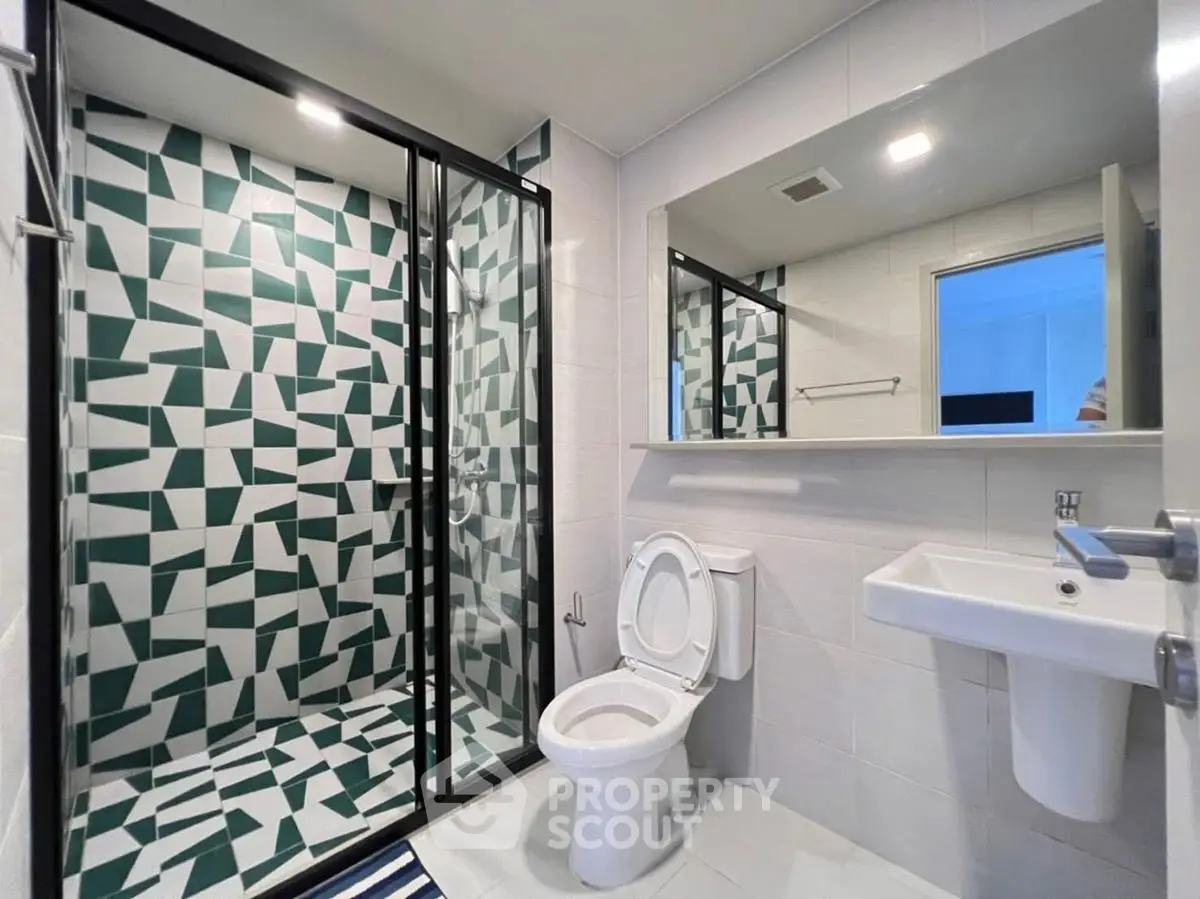 Modern bathroom with geometric tile shower and sleek fixtures.