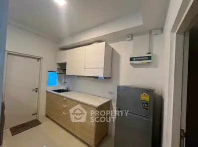 Modern kitchen with sleek cabinetry and stainless steel fridge in a compact layout.