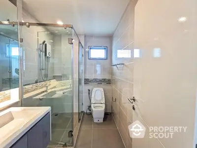 Modern bathroom featuring a glass-enclosed shower, sleek fixtures, and neutral tiles, offering a serene and contemporary space for relaxation.