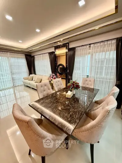 Luxurious open living and dining area with elegant marble table and plush seating.