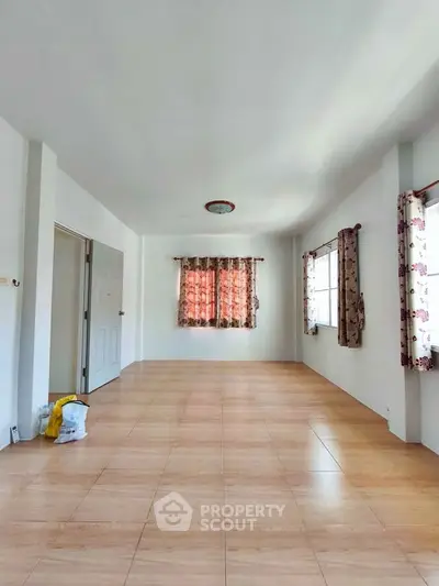 Spacious empty room with tiled flooring and floral curtains, ideal for customization.
