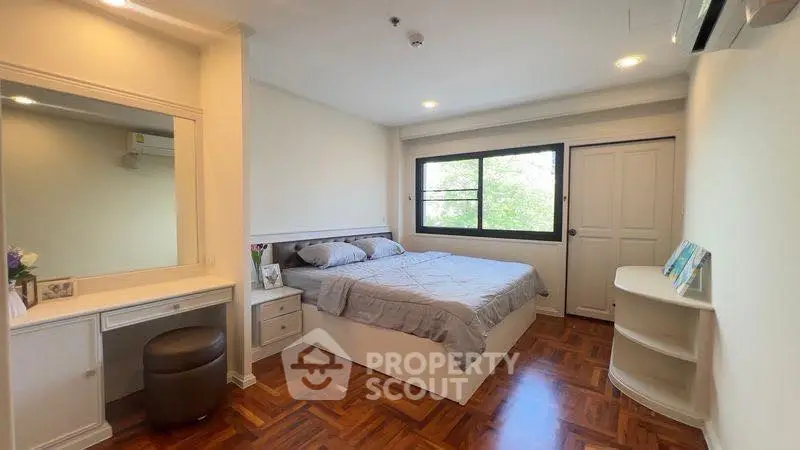 Spacious bedroom with elegant wood flooring and natural light