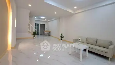 Spacious modern living room with elegant white decor and cozy seating area.