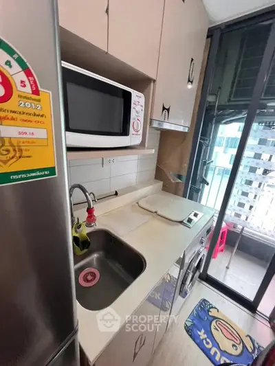 Compact kitchen with modern appliances and balcony access in urban apartment