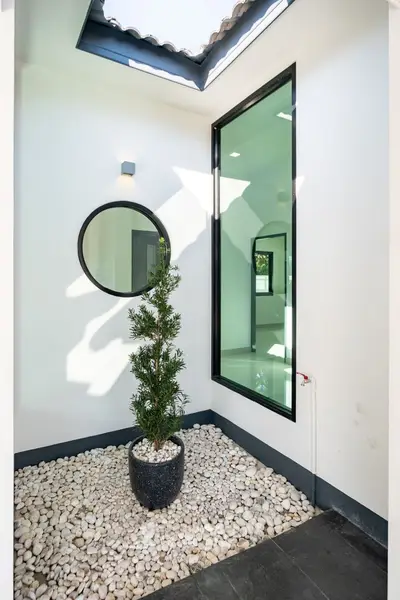 Modern minimalist courtyard with skylight and potted plant on pebbled ground.