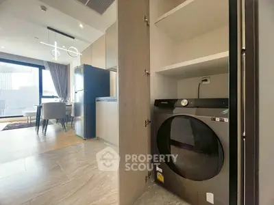 Modern apartment interior with open kitchen and built-in washing machine, featuring stylish lighting and large windows.