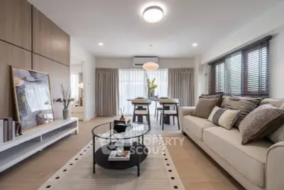 Modern living room with stylish decor and open dining area, featuring neutral tones and natural light.