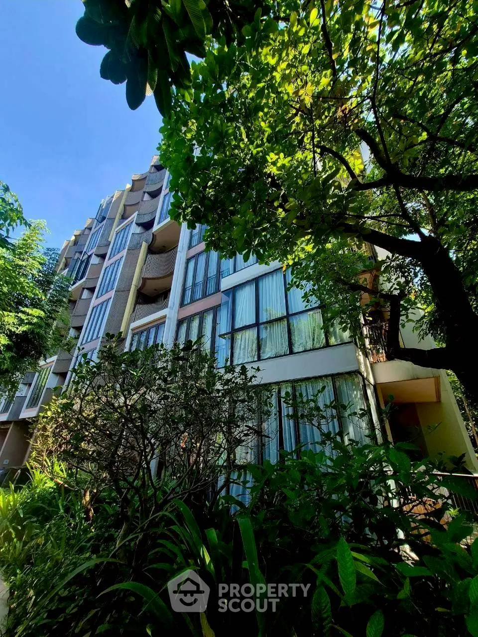 Modern apartment building with lush greenery and large windows