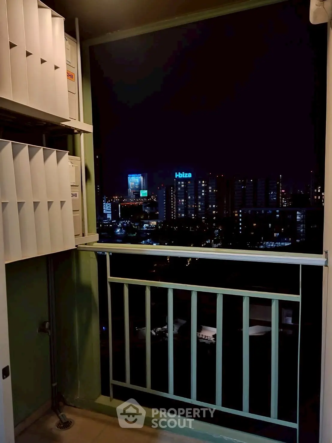 Night view from a high-rise balcony overlooking city skyline with modern buildings.