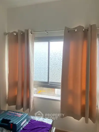 Cozy bedroom with large window and elegant curtains, perfect for natural light lovers.